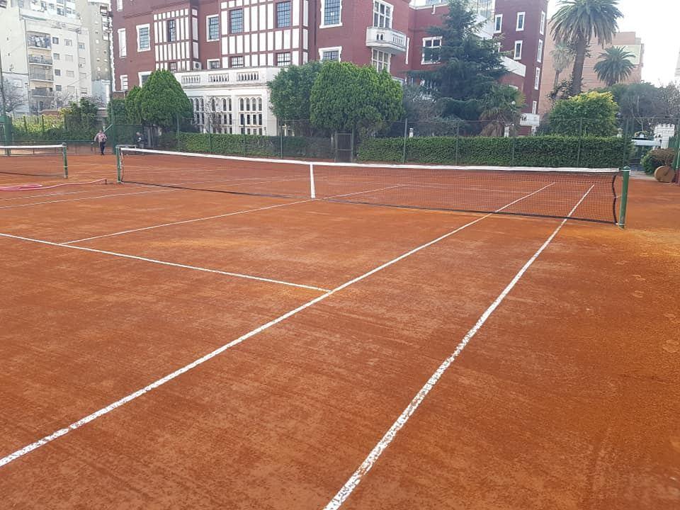 Cancha de tenis de polvo de ladrillo entre edificios